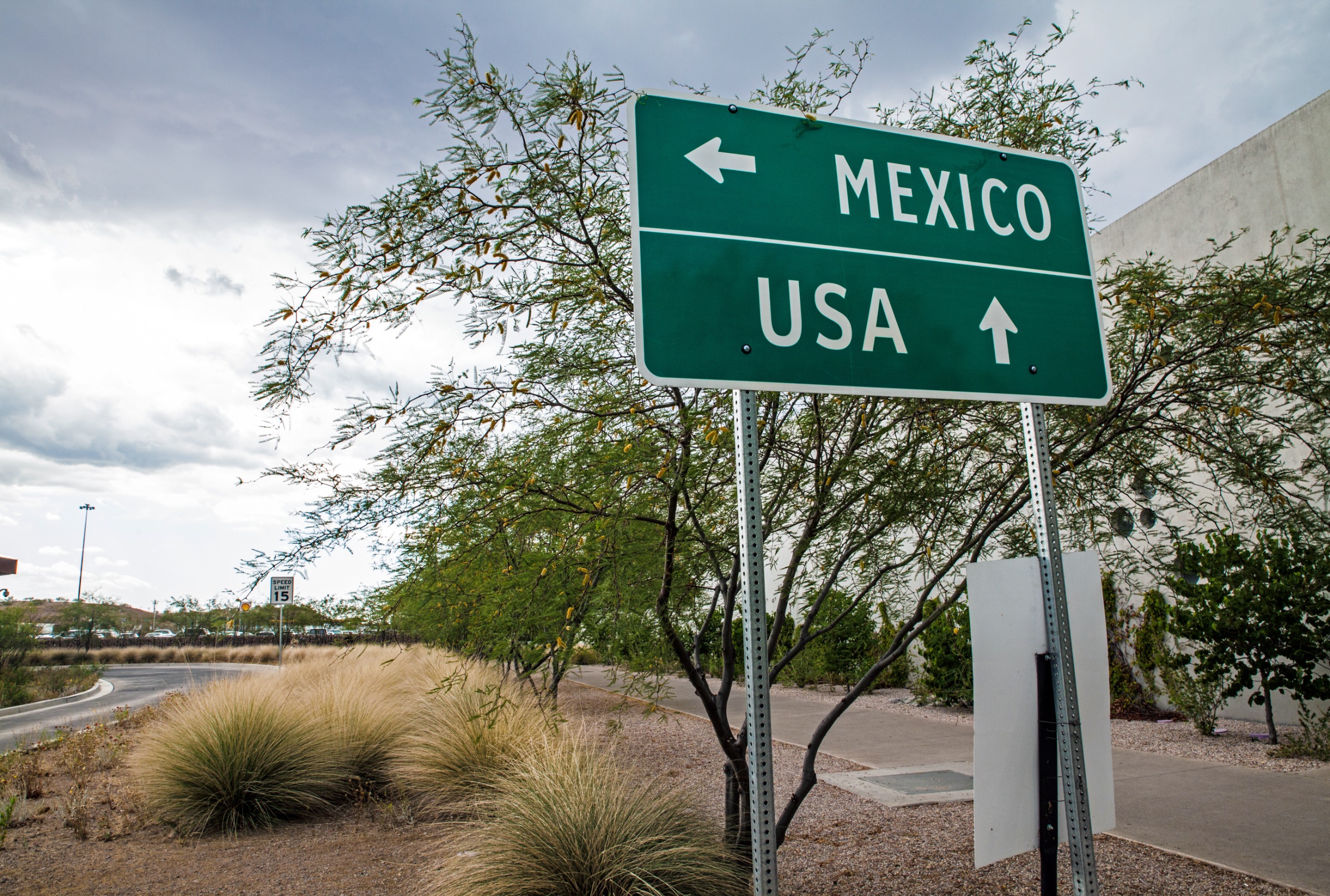 An image of a green sign that reads "Mexico" with a right arrow and "USA" with a forward arrow.